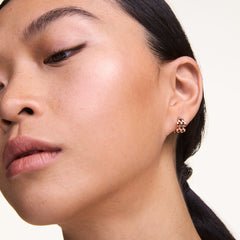 A woman wears a Daniel Wellington 5-Link Earring in rose gold, showcasing the mini hoop’s bold open link design and polished finish against her ear for a modern, elegant look.