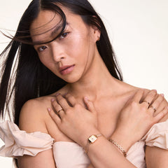 A woman wearing the Quadro Mini Melrose Champagne watch with a rose gold mesh strap, styled alongside matching jewellery and a light off-shoulder top, highlighting its petite rectangular champagne dial and elegant minimalist design.