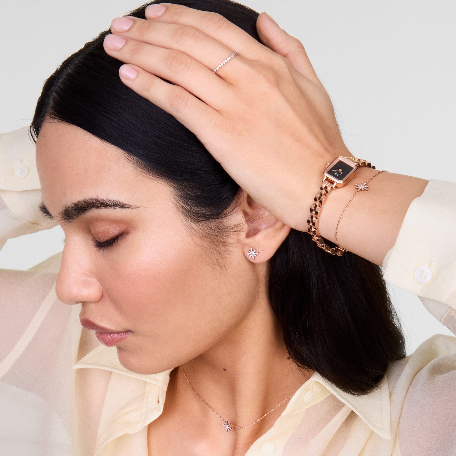 Quadro Mini Arch 3-link Onyx Sunray Rose Gold ladies watch styled on a wrist with matching rose gold jewellery, showcasing its petite rectangular case, black sunray dial, and three-link bracelet for a coordinated and elegant look.