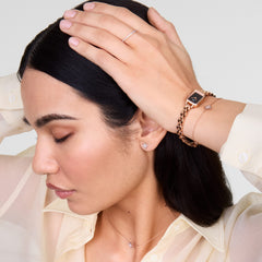 Quadro Mini Arch 3-link Onyx Sunray Rose Gold ladies watch styled on a wrist with matching rose gold jewellery, showcasing its petite rectangular case, black sunray dial, and three-link bracelet for a coordinated and elegant look.