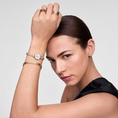 A woman wearing the Petite Mini Arch 3-link White Gold watch on her wrist, styled with matching gold jewellery including a bracelet, ring, and earrings, highlighting the petite gold case and crisp white dial for an elegant, coordinated look.