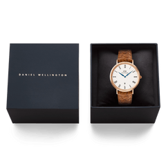 Classic Roman Numerals Date Light Brown Croc Belly Rose Gold watch presented in a black Daniel Wellington gift box, featuring a rose gold case, white dial with Roman numerals, blue hands, and a light brown croc-embossed leather strap.