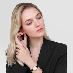 A woman wearing the Ophelia Mini Dark Brown Lizard White Guilloché Gold watch, styled with a black blazer, showing the petite oval gold case and dark brown lizard-embossed leather strap for a refined, elegant look.