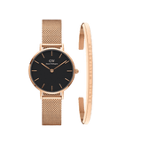 Rose gold ladies watch with a black dial and adjustable mesh strap, paired with a slim rose gold bracelet engraved with Daniel Wellington, presented as a coordinated jewellery set.