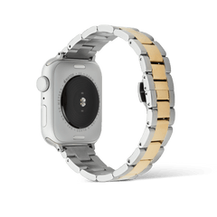Smartwatch Iconic Link two-tone strap attached to an Apple Watch, highlighting the polished gold centre links and brushed silver outer links with a butterfly buckle, designed for durability and comfort.