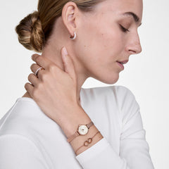Woman wearing the Classic Unity Lumine rose gold bracelet with intertwined rings and crystal accents, styled alongside a matching rose gold watch and minimalist jewellery for an elegant, everyday look.