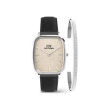 The Marlon Sheffield Linen & Classic Bracelet Silver set features a men’s watch with a cushion-shaped silver case, linen-textured yellow dial, black leather strap, and a slim polished silver bracelet engraved with the Daniel Wellington logo.