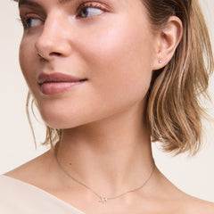 A woman wears the Crystal Zodiac Chain Necklace Silver, featuring a minimalist silver chain and a sparkling Sagittarius zodiac pendant with hand-set crystals, styled for an elegant everyday look.