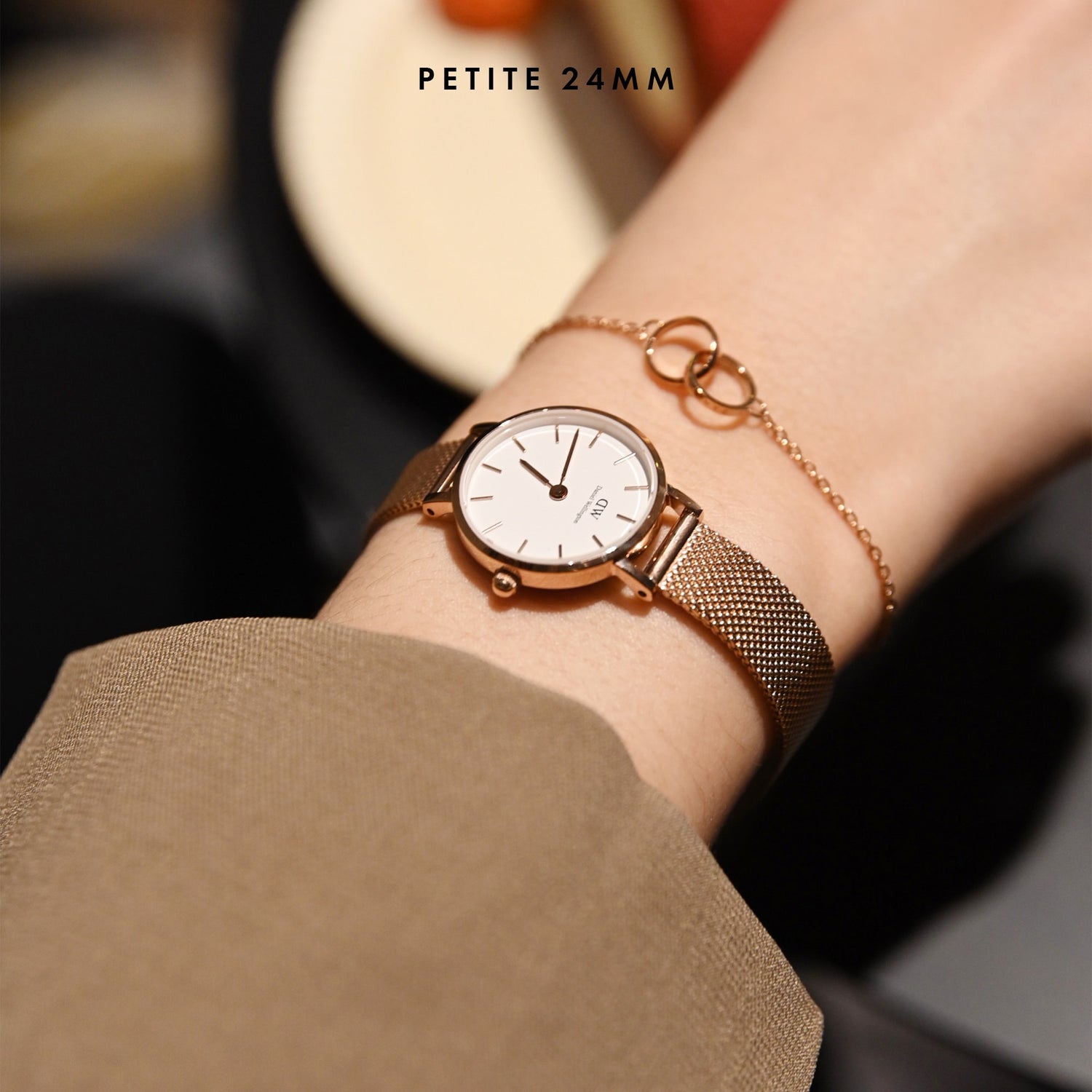 Petite Pressed Melrose Rose Gold watch with a 24mm rose gold mesh strap, worn on a woman's wrist alongside a delicate rose gold bracelet, showcasing its refined and comfortable fit for everyday wear.