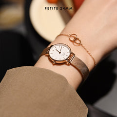 Petite Pressed Melrose Rose Gold watch with a 24mm rose gold mesh strap, worn on a woman's wrist alongside a delicate rose gold bracelet, showcasing its refined and comfortable fit for everyday wear.