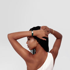 A woman wearing the Bound Mini Green Lizard Gold watch, showing its slim green lizard-embossed leather strap and gold rectangular case styled with a white dial, paired with gold jewellery for a modern, elegant look.