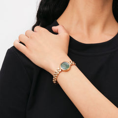 A woman wearing the Elan Lumine Malachite Rose Gold watch with a petite rose gold bracelet and a distinctive green malachite dial, styled with a black top for a modern, elegant look.