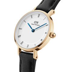 Close-up of the Petite Roman Numerals Sheffield Gold watch showing its gold-plated case, crisp white dial with Roman numerals, blue steel hands, and a slim black leather strap.