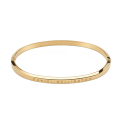 Classic Bangle Gold is shown with a polished gold finish and minimalist silhouette, featuring Daniel Wellington branding engraved on the outer edge and a discreet hinge for secure fastening.