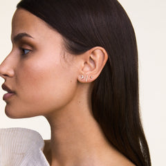 The Crystal Bar Stud Silver earring is shown worn in a curated ear stack, highlighting its slim silver bar set with seven cubic zirconia crystals for a minimalist, sparkling accent suitable for everyday wear.