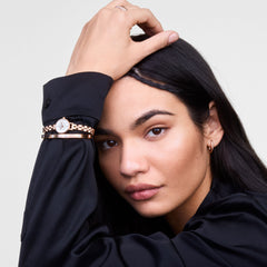 Petite Mini Arch 3-link White Rose Gold watch styled on a woman's wrist alongside a matching rose gold bracelet, highlighting its slim design and crisp white dial for an elegant, modern look suitable for everyday wear.