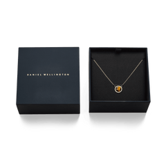 Audrey Necklace Tiger Eye Gold displayed in an open Daniel Wellington box, highlighting the gold chain and tiger eye pendant with cubic zirconia accents, next to the branded lid.