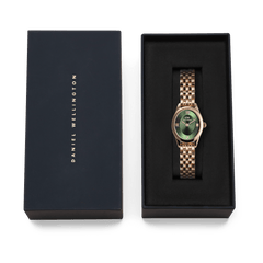 Ophelia Mini Emerald Rose Gold watch with an oval case and beans link bracelet, presented in a black Daniel Wellington gift box, highlighting its emerald green dial and polished rose gold finish.