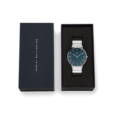 Classic Piano Link Arctic Silver watch with a brushed arctic blue dial and stainless steel piano link strap, presented in a black Daniel Wellington gift box.