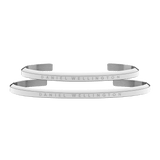 Two slim, polished silver cuff bracelets with the Daniel Wellington logo engraved along the surface, featuring a minimalist and refined design suitable for both men and women.