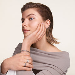A woman wears the 5-Link Ring Silver on her finger, styled with matching silver jewellery and a neutral outfit, highlighting the ring’s geometric link design and polished finish in a modern, everyday look.