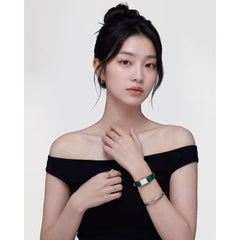 A woman wearing the Daniel Wellington Arch Earring Silver 12mm, styled with a black off-shoulder top and paired with silver rings, a silver bangle, and a green strap watch for a modern, minimalist look.