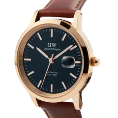 Close-up of the Iconic St Mawes Automatic Rose Gold watch, showcasing its blue enamel dial, rose gold-plated stainless steel case, and brown Italian leather strap with luminous markers and date window.
