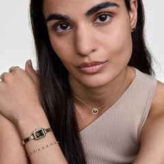 A woman wears the Quadro Mini Reflection Gold watch with a slim rectangular gold case and mesh strap, styled alongside gold jewellery for a sophisticated everyday look.