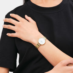 A woman wearing the Petite Roman Numerals 5-Link Gold watch, featuring a slim gold bracelet and a white dial with Roman numerals and blue steel hands, styled with a casual black top.