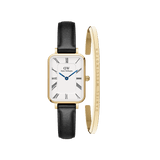 Rectangular gold-framed watch with a white dial, black Roman numerals, blue hands, and a black leather strap, paired with a slim gold bracelet engraved with the Daniel Wellington name.