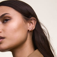 Moon Stud Rose Gold earring styled in a second piercing, paired with other rose gold and crystal earrings, showcasing its petite crescent shape and polished finish for a layered, modern look.
